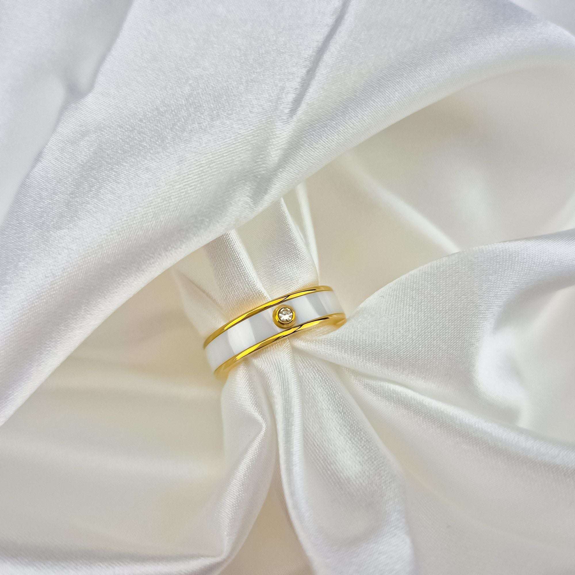 Elegants gredzens zelta tonī ar balto keramiku, stilīgai un izsmalcinātai nēsātājai