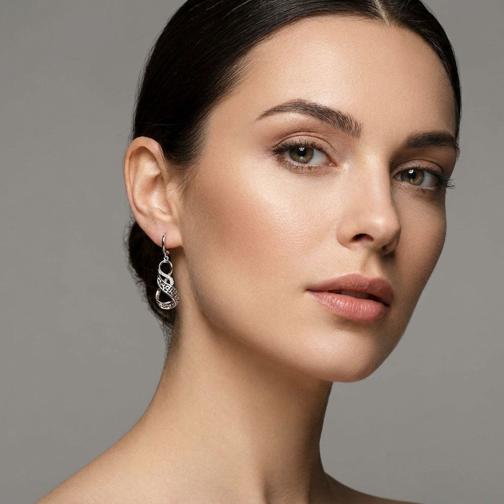 Modelis nešioja kabančius auskarus su graikišku raštu, sidabro tonu pilkame fone